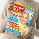 Person in beigem Strickpullover hält das Magazin „auf einen Blick“ mit rotem Logo auf hellblauem Hintergrund. Cover zeigt eine blonde, weibliche Person mit gelbem Spitzenoberteil lächelnd nach vorne. Überschriften u. a.: „Geld verdienen in der Rente“, „Das Super-Frühstück gegen Demenz“, „Küchenmaschinen im Check“, „Sommer-Nudeln für Genießer“, „Welche Schmerz-Therapie hilft mir wann?“ und „Die Top 7 der Woche“.