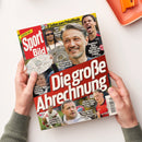 Titelblatt der Zeitschrift „Sport Bild“ mit rotem Hintergrund und großem weißen Schriftzug „Die große Abrechnung“. Mehrere männliche Fußballpersonen sind abgebildet, im Mittelpunkt ein grauhaariger Mann mit Sieger-Teller. Weitere Texte: „Kovac exklusiv: So haben wir die Wende gepackt“, „Olise war Bayerns Bester“, „Wirtz-Poker: Geheimgipfel in den USA“. Gehalten von zwei Händen über hellem Tisch mit orangefarbenem Tablett.