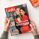 Titelbild der Zeitschrift „Gala“, Ausgabe April 2023, zeigt zwei umarmende Frauen vor dunklem Hintergrund, beide in roten Kleidern. Hauptüberschrift in Weiß: „Kraftvolle RÜCKKEHR“. Weitere sichtbare Textelemente: „Applaus & Protest“, „Wedding ISSUE“, „Sie will es allen beweisen“ sowie kleinere Bilder und Schriftzüge zu Themen über Prominente, Musik und Familie. Gehalten von zwei Händen über hellem Tisch mit oran­gener Schale.