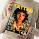 Magazin „Tattoo Life“ mit gelb-weißem Titel auf grünem Hintergrund, gehalten von einer Person in beigefarbenem Strickpullover. Auf dem Cover eine weiblich gelesene Person mit dunklem Haar, Nasen- und Lippenpiercings sowie sichtbaren Hals- und Brusttattoos. Sichtbare Texte u. a.: „Cover Girl Alexa Tamaska“, „Tattoo Shop Sinked Art Pordenone“, „Fotografische Malerei von Janina Antton“, „Industriy Zwischen Farben“ und „Tony Kaprinski“.
