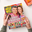 Titelbild der Zeitschrift „NEUE WELT – Für die Frau“ mit einem lächelnden Mann in rosafarbenem Hemd und einer lächelnden Frau in blauem Oberteil vor gelbem Hintergrund. Überschriften u. a.: „Andy Borg – Liebessensation“, „Prinzessin Kate – Süße Baby-Gerüchte“, „König Frederik – Geheimes Doppelleben“, „Thomas Gottschalk – Pikante Beichte“ sowie Hinweis auf „Kuchen wie im Landcafé“. Hände halten das Magazin über einem hellen Tisch.