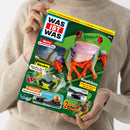 Person in beigefarbenem Strickpullover hält das Magazin „WAS IST WAS“ Nr. 5 mit grünem Titelhintergrund; zentral ein großer, farbenfroher Baumfrosch mit roten Augen und orangefarbenen Füßen, daneben Text „Amphibien – Leben im Wasser und an Land“. Weitere Themen auf dem Cover: „Wetter – Zerstörerische Winde“, „Märchen – Menschen, die zu Tieren werden“, „Seeotter – Schlau und dickes Fell“, „2 tolle Poster“.