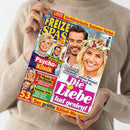Hände einer hellbeigen gekleideten Person halten das Magazin „Freizeit Spass“. Auf dem bunten Cover mit gelbem, blauem und pinkem Layout sind mehrere Porträts zu sehen, unter anderem eine blonde lächelnde Frau mit Blumenkranz und ein lächelnder Mann. Sichtbare Texte: „Die Liebe hat gesiegt“, „Psycho-Klinik“, „53 Super-Rätsel“, „Verführerische Sommer-Torten“ und „Das größte Rätsel-Magazin“.