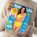 Titelblatt der Zeitschrift „Women’s Health“, gehalten von einer Person mit beigefarbenem Strickpullover. Auf dem Cover steht eine lächelnde Frau in gelbem Badeanzug vor blauem Hintergrund. Sichtbare Texte: „Easy schlank in 15 Minuten“, „Jana Ina Zarrella“, „Lebe fit & happy“, „100 % Sommer“, „Glow-Guide für schöne Haut“, „Gesundes BBQ leicht gemacht“ und „Die schönste Beachwear für jede Figur“.