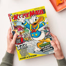 Titelbild des Comics „Micky Maus Magazin“. Im Vordergrund eine Comic-Illustration von Donald Duck in blauem Matrosenanzug mit erhobenen Armen, im Hintergrund weitere Entenfiguren vor einem Haus. Aufdrucke: „Walt Disney Micky Maus“, „W.I.T.T. Elefant-H-H-H-Atschi!“, „Die Nicht-Lachen-Challenge“ und „Die große Witze-Battle!“. Gelber Hintergrund mit farbigen Comiczeichnungen, gehalten von zwei Händen vor hellem Tisch.