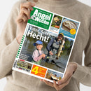 Titelblatt der Zeitschrift „AngelWoche“ (Ausgabe 12/2025) mit grün-weißem Logo oben. Hauptmotiv zeigt einen erwachsenen Mann und ein Kind beim Angeln im seichten Wasser, der Mann hält einen großen Hecht. Text: „Vater, Sohn, Hecht!“. Weitere sichtbare Überschriften: „Mehr dazu im Foto-Report auf Seite 6“, „Köder für Hornis“, „Dicke Rapfen auf Krebse“ und „Wie macht man leckere Matjes zu Hause?“.