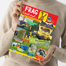Person in beigem Strickpullover hält das Magazin „FRAG doch mal… Das Wissensmagazin“ mit rotem Titelkopf und der Figur der Maus. Auf dem Cover: großformatiges Foto eines schwarz-gelb gefleckten Salamanders, kleinere Bilder eines Schuhmachers, einer begrünten Fassade, eines Geparden, eines Motorrads und zweier Poster. Textelemente u. a.: „SALAMANDER! Was haben sie mit Feuer zu tun?“, „Schuhmacher!“, „Gärten!“, „2 Poster“.