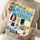 Person in beiger Strickpullover hält das Magazin „Bastei Glücks Rätsel“ mit gelbem Titelblatt und blauer Schrift. Sichtbar sind mehrere Abbildungen: Porträt einer lächelnden Frau, ein Rätselgitter, Fotos von Armbanduhr, Entsafter, Gläser-Sets, einer wandernden Person und einem Buchcover „Schwestern aus Krakau“. Textausschnitte u. a. „Romane und Hörspiele“, „Urlaub“, „Garantie 115 Gewinne“, „Mai/Juni“ und „Nr. 3/25“.