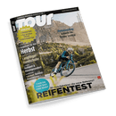 Titelblatt des Magazins „TOUR“, Ausgabe Nr. 10, thematisiert Rennsport und Herbstausflüge im Tiroler Lechtal; zeigt eine Person in blauem Radsportanzug, die auf einem Rennrad fährt, vor einer bergigen Landschaft. Die Schlagzeilen enthalten: „Herbstausflug: Graveln im Tiroler Lechtal“, „Langfinger-Handschuhe Test“, „Rennsport: Olympia Paris, Tour de France, Deutschland-Tour“ und „Reifentest: + mehr Grip + mehr Speed + mehr Komfort“.