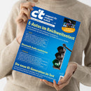 Person in beigem Strickpullover hält ein Exemplar des Magazins „c’t magazin für computer technik“ mit blauem Titelblatt in der rechten Hand. Sichtbare Texte: „E-Autos im Reichweitentest“, „Bluetooth-Audio nachrüsten“, „Die neue KI-Generation im Test“. Abgebildet sind eine schwarze Ampel mit grünem Lichtsignal und eine kleine TV-Bildschirmgrafik mit der Aufschrift „Der gläserne TV-Zuschauer“.