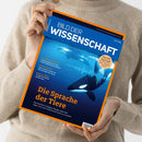 Helle Person in beigefarbenem Strickpullover hält vor neutralem Hintergrund das Magazin „Bild der Wissenschaft“ (Ausgabe 06/2025) in beiden Händen. Das Cover zeigt mehrere Orcas in blauer Unterwasserumgebung mit Schallwellenmustern, orangefarbenen Titeln „Die Sprache der Tiere“ und Unterzeilen zu Themen wie „Galaxien-Superhaufen“, „DNA-Analysen“ und „Biogas-Anlagen“, oben mit orange umrandetem Design.