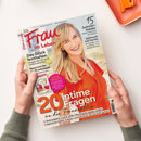 Titelblatt der Zeitschrift „Frau im Leben“, gehalten von zwei Händen über einer hellen Oberfläche; im Mittelpunkt eine lächelnde Frau mit blondem Haar in orange-rotem Oberteil. Text auf dem Cover: „Das Glück festhalten“, „15 Sommer-Kleider“, „Schmuck mit Perlen“, „SÜSSE FRÜCHTE“, „20 intime Fragen an die Frauenärztin“, dazu Unterzeilen zu Gesundheit, Mode und Ernährung.