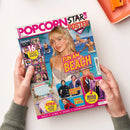Magazintitel „Popcorn Star & Poster“ mit farbenfrohem Cover; eine junge weibliche Person mit blondem Haar im Mittelpunkt vor Strand- und Wasserhintergrund, umgeben von kleineren Bildern bekannter Musiker*innen und Schauspieler*innen. Sichtbare Texte: „FUN AM BEACH – Wo Stars den Sommer feiern“, „16 coole Poster“, „Mega-Hype um BTS“, „Spidey is back“, „Extra: 2 coole Wochenpläne“, „Quiz“, „Kino“, „News“, „Starhoroskop“.