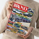 Helle, langärmlig gekleidete Person hält das Magazin „OFF ROAD – Das 4x4-Magazin für die Freiheit auf Rädern“ in beiden Händen vor neutralem Hintergrund. Das Titelblatt zeigt mehrere Geländewagen, Überschriften wie „Toyota Land Cruiser 70“, „DER VIELLEICHT BESTE J7 ALLER ZEITEN“, „MEHR HUB, MEHR ZUG“ und Themenfelder zu Tests, Additiven, Bolivien sowie Offroad-Events in farbiger, bildreicher Gestaltung.