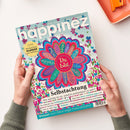 Magazin „happinez – das Mindstyle Magazin“ in den Händen einer Person vor hellem Hintergrund, mit bunter Titelseite, die ein mandalaähnliches Blütenmotiv in Rosa, Blau und Grün mit dem zentralen Text „Du bist“ und umliegenden Begriffen wie „einzigartig“, „smart“, „lebendig“, „besonders“ zeigt; Titelthemen u. a. „Selbstachtung“, „Wie wichtig ist es, wirklich authentisch zu sein?“ und ein gelber Kreis mit dem Hinweis „Extra wunderschönes Kraftbild zum Aufhängen“.
