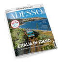 Titelbild der Zeitschrift „Adesso“ mit dem Schriftzug „ZEIT SPRACHEN“ oben. Im Vordergrund ein blau-grüner Zug auf einer eingleisigen Bahnstrecke entlang der italienischen Küste, umgeben von grüner Vegetation, Meer und Hügeln im Hintergrund. Textaufschriften: „L’ITALIA IN TRENO – 8 spektakuläre Zugstrecken für Ihren Urlaub“, „FIT IN ITALIENISCH! Wortschatz für die Zugfahrt“, „MUSICA“ und „L’INTERVISTA Stefano Polato“.