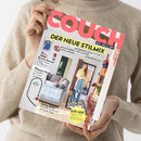 Beige gekleidete Person hält die Zeitschrift „COUCH – Alles, was du liebst“ vor neutralem Hintergrund; Titelüberschrift „DER NEUE STILMIX“ mit Themen zu modernem Boho-Style, Beauty-Spezial, Pflanzen-Guide, Dating 2025 und Oster-Ideen. Auf dem Cover: wohnlich eingerichtetes Zimmer mit Couch, Deko und einer weiblichen Person in heller Bluse und blauer Hose.