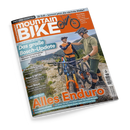 Titelblatt des Magazins „MountainBIKE“ mit orange-weißem Schriftzug auf orangem Hintergrund. Im Vordergrund zwei männliche Personen mit Fahrradhelm, Sportkleidung und Mountainbikes auf steinigem Bergweg, geben sich per Faustgeste die Hand. Sichtbare Schlagzeilen: „Das große Bosch-Update“, „Rucksack-Check“, „Neue E-MTBs“, „Tour Royal“ und groß unten „Alles Enduro“. Im Hintergrund Berge und blauer Himmel.