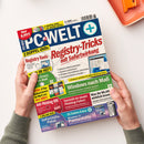 Titelblatt der Computerzeitschrift „PC-WELT+“, Ausgabe 8/2026, mit mehrfarbig gestaltetem Layout in Blau, Rot, Gelb und Grün. Hauptüberschrift „Registry-Tricks mit Sofortwirkung“, weitere sichtbare Textelemente wie „Windows nach Maß“, „Registry-Tools“, „Anti-Phishing-DVD“, „Soforthilfe-Paket“ und „Windows 11 Pannenhilfe“. Gehalten wird das Heft von zwei Händen über einer hellen Tischfläche mit orangener Ablageschale rechts oben.