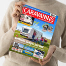 Person in beigefarbenem Pullover hält das Magazin „CARAVANING – Europas großes Camping-Magazin“, Ausgabe 6/2025, vor neutralem Hintergrund. Das Titelbild zeigt einen weißen Dethleffs Caravan 560 FMK auf einer Wiese mit zwei Erwachsenen und zwei Kindern davor, mit Überschriften u. a. zu neuen Eriba‑Modellen, Testberichten, Gadgets für Camper und Reisetipps entlang der Atlantikküste.