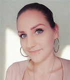 Frau mit zurückgebundenen Haaren und Ohrringen mit einem rosa weiß gestreiften Shirt.