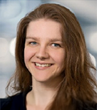 Porträt einer lächelnden jungen Frau mit langen braunen Haaren.