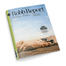 Titelbild der Zeitschrift „Robb Report“ (Deutsche Ausgabe, Nr. 38) mit hellblauem Himmel und staubiger Wüstenkulisse, im Vordergrund rechts ein weißer Supersportwagen mit schwarzen Akzenten in schneller Fahrt, aufwirbelnder Sand; großflächiger Text im Kasten: „WER BREMST, VERLIERT – Wie teuer alles ist und was wirklich wichtig bleibt“; links oben Magazinname, darunter Themenüberschriften zu Luxusreisen, Weinen und Restaurants; Rückseite grün gestaltet.