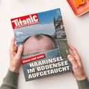 Titelblatt des Satiremagazins „Titanic – Das endgültige Satiremagazin“ mit einem Foto, das den oberen Teil eines männlichen Kopfes mit kreisförmiger Haarinsel zeigt, der aus einer Wasseroberfläche ragt; im Hintergrund sind See, Himmel mit Wolken und Gebäude mit Türmen am Ufer sichtbar. Auf der Titelseite steht der Text „Niveau sinkt weiter – Haarinsel im Bodensee aufgetaucht“.