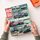 Aufgeschlagenes Autozeitschriften-Cover „Auto Bild“ mit türkisfarbenem Hintergrund und zahlreichen Fahrzeugabbildungen. Sichtbare Texte: „Europas Nr. 1“, „Test Hyundai Ioniq 6 N“, „Benzin oder Strom? Peugeot 308 SW“, „Gecheckt: gebrauchte Kompakt-SUV“, „Getestet Mercedes GLA gegen BMW 220“, „Gefahren Audi Q7“, „Gebraucht Mazda CX-60“, „Dachzelte im Test“ und „Faszination Porsche 964“; gehalten von zwei nicht eindeutig geschlechtlich zuordenbaren Händen neben einem orangefarbenen Gegenstand.