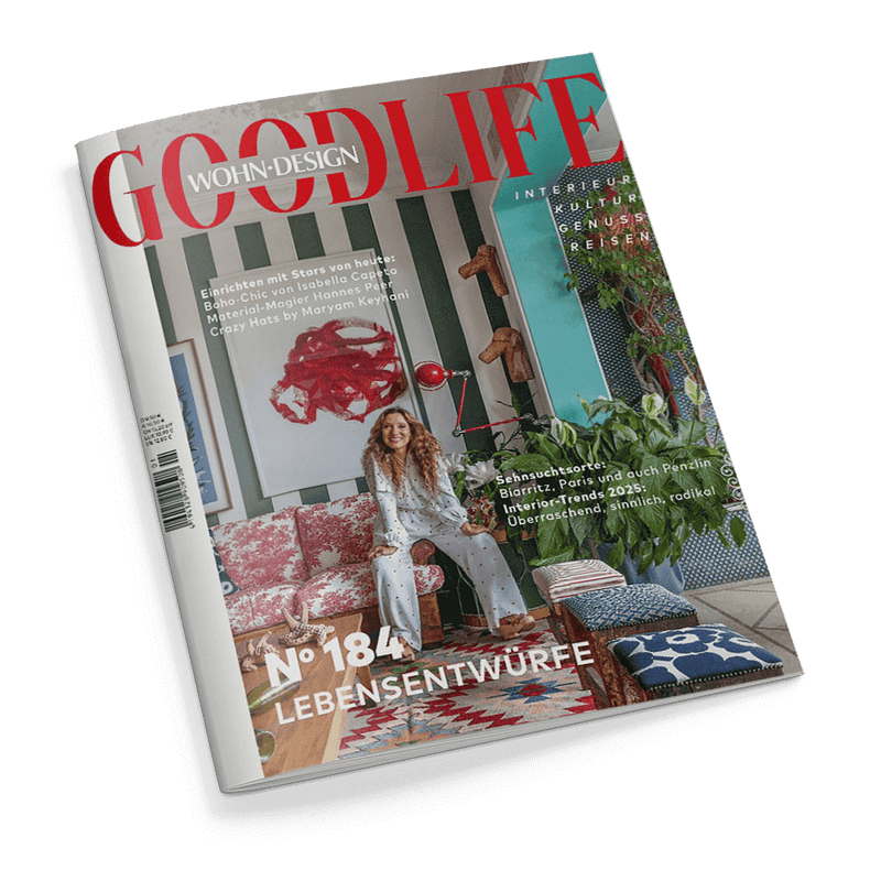Titelbild der Wohn- und Designzeitschrift „GOODLIFE“, Ausgabe Nr. 184 mit dem Schwerpunkt „Lebensentwürfe“, zentrale Abbildung einer sitzenden, langhaarigen Frau in heller Kleidung auf einem gemusterten Sofa vor grün-weiß gestreifter Wand mit großem abstrakten Kunstwerk und mehreren Wanddekorationen; sichtbare Texte zu Themen wie Boho-Chic, Interior-Trends 2025, Sehnsuchtsorte und Material-Design, rechts im Bild üppiges Grünpflanzenarrangement und bunt gemusterte Sitzkissen.