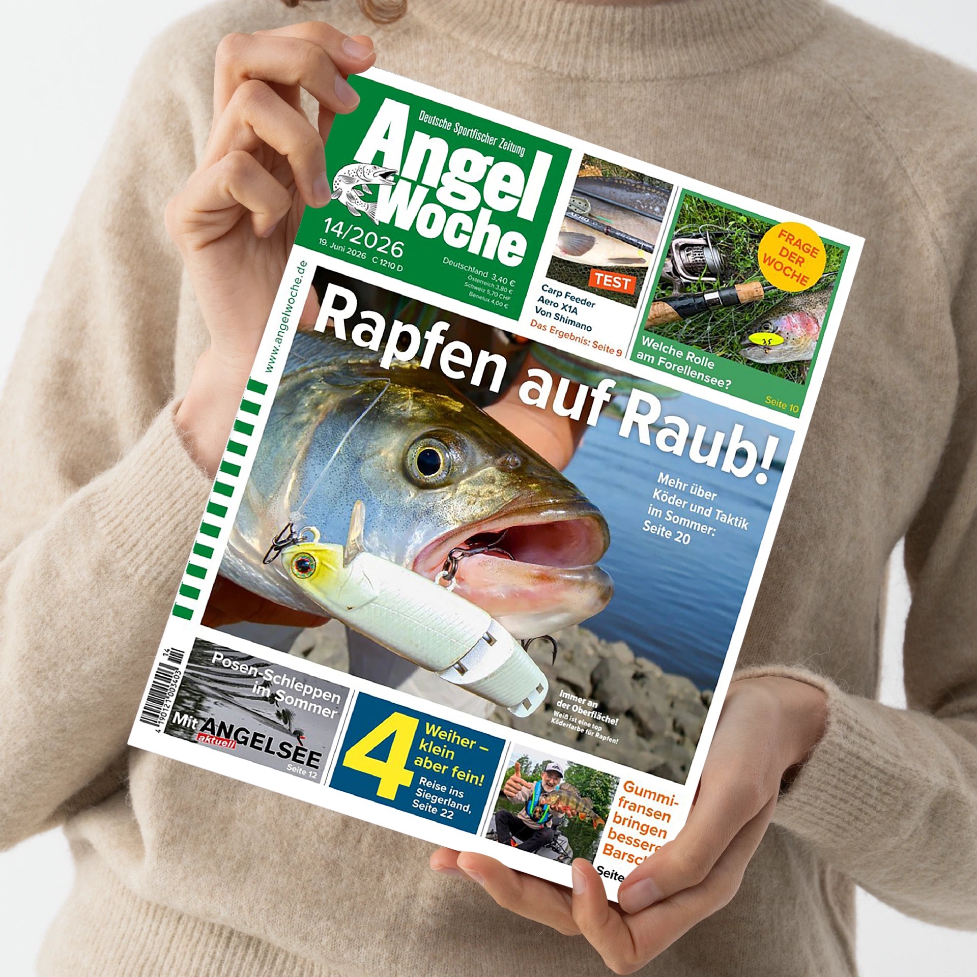 Person in beigefarbenem Strickpullover hält das Magazin „AngelWoche“, Ausgabe 14/2026. Titelbild mit großem Fischkopf mit weißem Kunstköder im Maul vor Wasserhintergrund, Hauptüberschrift „Rapfen auf Raub!“. Zusätzliche Texte: „Mehr über Köder und Taktik im Sommer: Seite 20“, „Posen-Schleppen im Sommer“, „4 Weiher – klein aber fein!“, „Welche Rolle am Forellensee?“ und weitere Themen im oberen grünen Kopfbereich.