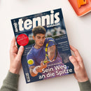 Titelblatt der Zeitschrift „tennis MAGAZIN“ mit großem Foto eines männlichen Tennisspielers in violettem Shirt beim Vorhandschlag, gelber Ball im Vordergrund, Hintergrund unscharf. Texteinblendungen: „Carlos Alcaraz – Sein Weg an die Spitze“, „Jasmine Paolini – So lief ihr steiler Aufstieg“, „Tennisarm – Mit neuen Therapien den Schmerz besiegen“ sowie roter Kreis mit „PLUS großer Test – So gut sind die neuen Tennisschuhe“. Zwei Hände halten das Magazin über hellem Untergrund.