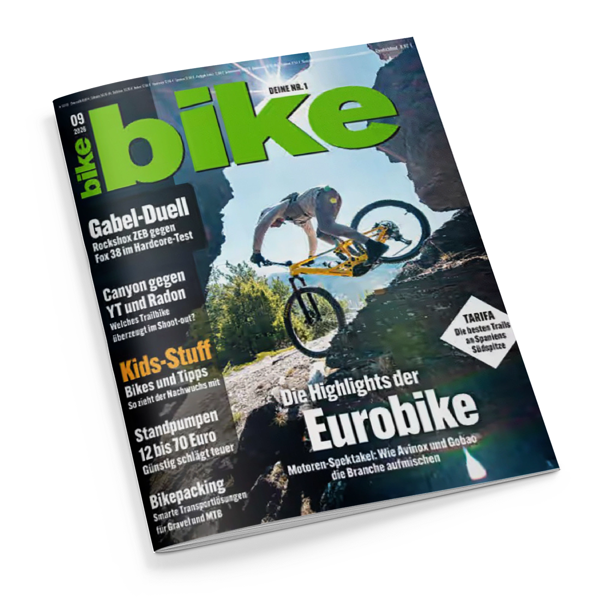 Schräg fotografiertes, glänzendes „bike“-Magazin auf schwarzem Hintergrund mit großem grünem Titel „bike“ und Aufschrift „DEINE NR.1“. Das Cover zeigt eine männliche Person auf einem gelben Mountainbike beim Sprung über felsiges Gelände; lesbare Überschriften sind „Gabel-Duell“, „Canyon gegen YT und Radon“, „Kids-Stuff“, „Bikepacking“, „Eurobike“ und „TARIFA“.
