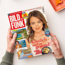 Zeitschrift „BILD der FRAU“ mit dem Titel „TV-Zeitschrift & Illustrierte“ und dem Hinweis „Ihr Fernseh-Programm vom 22.8. bis 28.8.2026“, schräg auf weißer Fläche liegend und von zwei Händen gehalten. Das Cover zeigt eine Frau mit braunem Haar und blauen Augen sowie Texte wie „NEU! 60 TV-Sender extragross“, „Fußball-Bundesliga-Planer Saison 2026/27“, „Köstlich – und so gesund!“ und „Raffinierte Rezeptideen mit Fisch“.