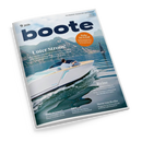 Schräg fotografiertes Magazin „boote“ mit weißem Cover auf schwarzem Hintergrund: Ein weißes Motorboot mit einer männlichen Person fährt über blaues Wasser vor einer Berglandschaft, im Hintergrund ist ein Segelboot erkennbar. Sichtbare Texte: „Unter Strom!“, „Ruhe im Schiff“, „Reise“, „Im Test“, „Bootszeug?“ und „Stern von Berlin“.