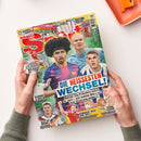 Schräg gehaltenes Fußballmagazin „BRAVO SPORT“ mit mehreren männlichen Fußballspielern sowie einem Basketballspieler auf dem farbigen Cover. Sichtbare Texte: „STICKERALBUM + 2. BUNDESLIGA“, „XI-SPORT-KALENDER“, „2 ACTION-POSTER“, „DIE HEISSESTEN WECHSEL!“ und „SEHNSUCHT NACH DEM TRIPLE“; zwei Hände halten das Heft über einer weißen Fläche, oben rechts liegt ein oranges Tablett.