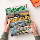 Titelbild der Zeitschrift „Auto Bild Klassik“ mit grün-weißem Logo im oberen Bereich; darunter drei kleine farbige Autos—orange, rot und gelb—nebeneinander auf einer Straße. Großschrift „DIE UNBEKANNTEN MICROCARS“ in Weiß und Gelb. Weitere Texte: „Opel Manta 400 und eine Beziehung fürs Leben“ sowie kleinere Schlagzeilen zu Oldtimern, Reisen und Tests. Zwei Hände halten das Magazin vor hellem Hintergrund.