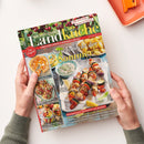 Titelblatt der Zeitschrift „Meine gute Landküche“ (Juli/August 2015) mit weißer Überschrift „So schmeckt der Sommer!“ über einem Bild von Grillspießen mit Gemüse und Dip-Schale auf hellblauem Untergrund. Weitere Bildfelder zeigen einen Pfirsich-Rosinen-Kuchen, gefüllte Paprikas und Getränke mit Obst. Oben Kirschdekor mit Texten „Süße und herzhafte Rezepte mit Kirschen“ und „Ländlicher Genuss & regionale Vielfalt“. Zwei Hände halten die Zeitschrift.