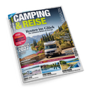 Schräg fotografierte Zeitschrift „CAMPING & REISE“ mit blau-grauem Cover und dem Titel „Routen ins Glück – Die schönsten Reisen in Europa“. Darauf: weißes Wohnmobil vor mediterraner Berglandschaft sowie Texte zu „Neuheiten 2027“, „Caravan Salon 2026“, „Hartschalendachzelt“, Vogtland, Münsterland, Südtirol, Auvergne und Finnland.