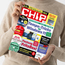 Weibliche Person im beigefarbenen Strickpullover hält eine schräg fotografierte CHIP-Zeitschrift mit rotem, weißem, gelbem und schwarzem Cover. Lesbare Titel: „Systemstart + Suche + Software“, „Tempo-Tricks für Windows 11“, „Festung FritzBox!“, „Gefahr oder Chance? Mythos-KI“ und „Praxis-Test: OpenClaw“; links sind mehrere Software-Datenträger abgebildet.