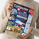 Weibliche Person im cremefarbenen Strickpullover hält eine schräg zur Kamera ausgerichtete Zeitschrift mit blau-schwarzem Digitalmuster. Auf dem Cover stehen „Computer Bild“, „30 Jahre“ und „DER FRITZBOX-WÄCHTER“; abgebildet sind unter anderem Router, Smartphones, eine Outdoor-Szene sowie weitere Technik- und Ratgeberthemen.