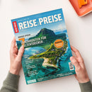 Titelbild der Zeitschrift „Reise & Preise“ mit blauem Hintergrund und Luftaufnahme einer tropischen Insel mit Bergen, Lagune und Küstenstreifen. Haupttitel „7 Traumrouten für Weltentdecker“, orangefarbener Kreis mit Text „Mauritius – Immergrüne Zuckerinsel“, weitere Aufschrift „City-Guide Paris“, „Spanien – Andalusien auf neuen Wegen“, „Kanada – Roadtrip durch British Columbia“ und „Extra Malediven, Botswana, Bosnien-Herzegowina“. Zwei Hände halten das Magazin.