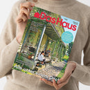 Weibliche Person im beigen Strickpullover hält eine schräg ausgerichtete Zeitschrift mit beiden Händen. Auf dem Titel „Das Haus“ stehen unter anderem „Farben & Tapeten: Frischer Wind für Ihre Wände“, „Solartechnik: Bereit für die Sonnenwende“, „Naturgärten: So schaffen Sie Lebensräume für Wildbienen, Igel und Co.“ und „Alle unter einem Dach“; abgebildet ist ein begrüntes Gewächshaus.