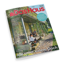 Schräg fotografiertes Cover der Zeitschrift „Das Haus“ mit rotem Logo und den Rubriken „BAUEN WOHNEN SCHÖNER LEBEN“. Abgebildet sind ein bepflanzter Wintergarten, eine sitzende Frau mit Kind und ein sitzender Mann; sichtbare Texte: „Naturgarten: So schaffen Sie Lebensräume für Wildbienen, Igel und Co.“, „Farben & Tapeten: Frischer Wind für Ihre Wände“, „Solartechnik: Bereit für die Sonnenwende“ und „Alle unter einem Dach“.