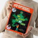 Weibliche Person im beigefarbenen Strickpullover hält ein schräg fotografiertes, orangefarbenes Magazin mit schwarzem Cover. Sichtbare Texte: „DEIN SPIEGEL“, „Durch Wissen wachsen“, „Im Interview Zehnkämpfer Leo Neugebauer“, „Wer bestimmt, was KI darf?“, „Im Sattel Viktoria Huld, 13, trainiert Pferde“ und „Von Fake News bis Fake Freunde – warum wir jetzt kluge Regeln brauchen“; zentral ist eine grüne Roboterfigur mit bunten Linien.