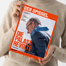 Beige gekleidete Person hält ein schräg fotografiertes Magazin mit orangefarbenem Rand. Auf dem Cover stehen „DER SPIEGEL“, „DIE PALAST-REVOLTE“ und „Union intern: Wie die eigene Partei an Merz verzweifelt“; abgebildet ist ein grauhaariger Mann mit Brille, blauem Schal und dunkler Jacke. Weitere Texte: „CSD-ANSCHLAG“, „GELDANLAGE“ und „ZEN-KLOSTER“.