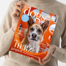 Orangefarbene Zeitschrift „DOGS today“ mit großem Hundefoto, gehalten von einer Person in einem beigefarbenen Strickpullover; das Geschlecht der Person ist nicht erkennbar. Sichtbare Texte: „TEST Wie schlau ist Ihr Hund?“, „VOM GLÜCK MIT HUND“, „GROSSES EXTRA“, „MOLVENO-SEE Geheimtipp in Norditalien“ und „HINTER DEN KULISSEN“.