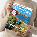 Person in beigefarbenem Wollpullover hält die Zeitschrift „ADESSO“ aus der Reihe „ZEIT SPRACHEN“ mit blauem Titelkopf und großem Foto eines blauen Zuges auf Küstenstrecke in Italien, flankiert von grüner Vegetation und Meer. Sichtbare Texte: „L’ITALIA IN TRENO“, „8 spektakuläre Zugstrecken für Ihren Urlaub“, roter Kreis mit „FIT IN ITALIENISCH – Wortschatz für die Zugfahrt“, sowie Rubriken „MUSICA“ und „L’INTERVISTA“.