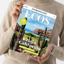 Weibliche Person in beigefarbenem Strickpullover hält eine schräg fotografierte Zeitschrift mit blauem Himmel, Meer, Felsen und mehreren Kakteen auf dem Cover. Sichtbare Texte: „SPANISCH“, „ZEIT SPRACHEN“, „ECOS“, „WORTSCHATZ Vacaciones en el Caribe“, „GRACIELA ITURRIBIDE Ihre Fotos verwandeln den Alltag in Poesie“, „Baja California“ und „Roadtrip in Mexiko von Tijuana bis Los Cabos“.