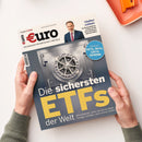 Aufgeschlagenes Wirtschaftsmagazin „€uro“ mit dem Logo „€uro“, der Aufschrift „Das Magazin für Wirtschaft und Geld“ und der Website „www.boerse-online.de“. Das Cover zeigt einen Tresor mit Zahnrädern, einen Mann im Anzug sowie Texte zu „Lindner exklusiv“ und „Die sichersten ETFs der Welt“; zwei Hände halten das Magazin, daneben liegt ein orangefarbenes Notizbuch.